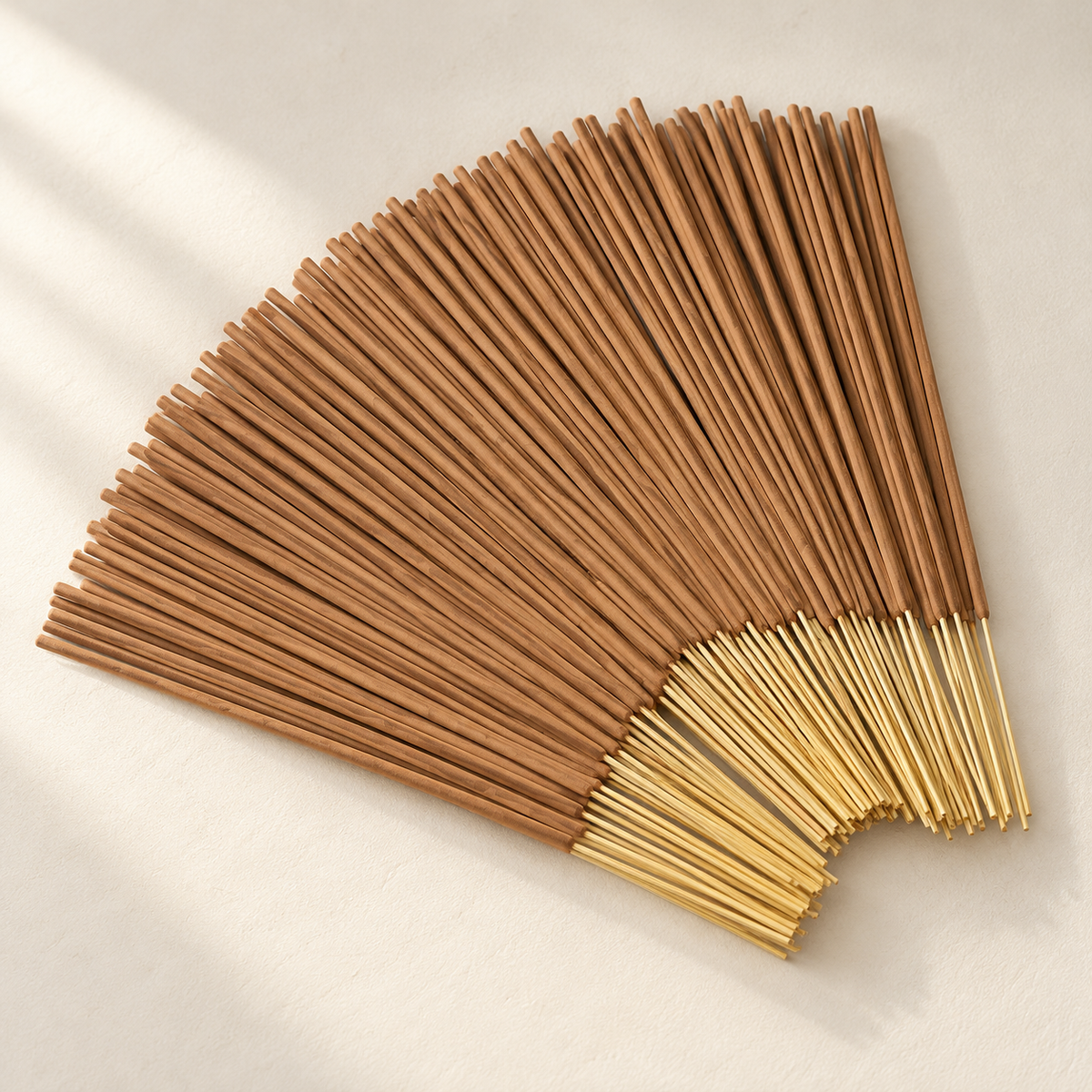 Sandalwood incense sticks fanned out on a warm off-white surface